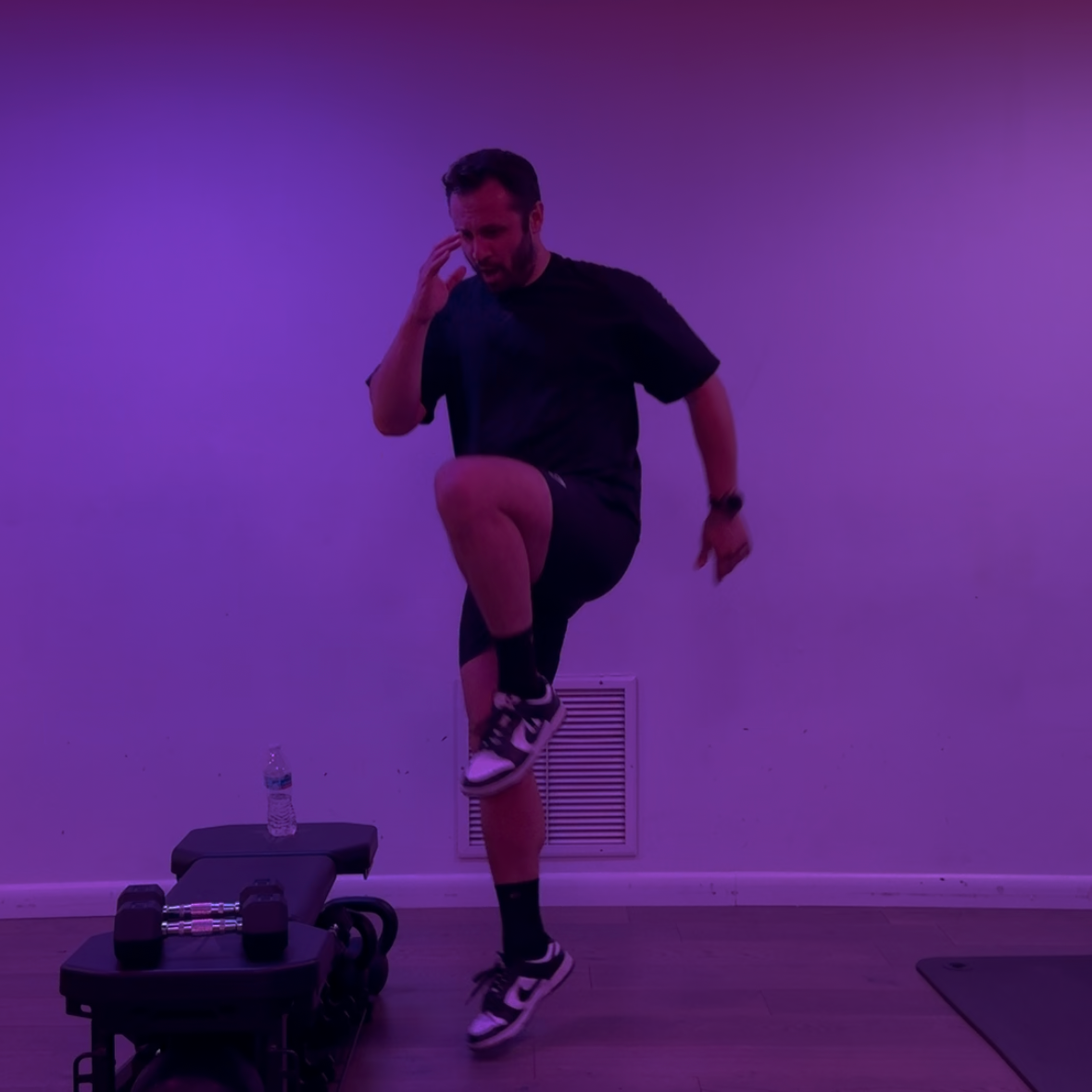 Person exercising on a step machine in a room with purple lighting